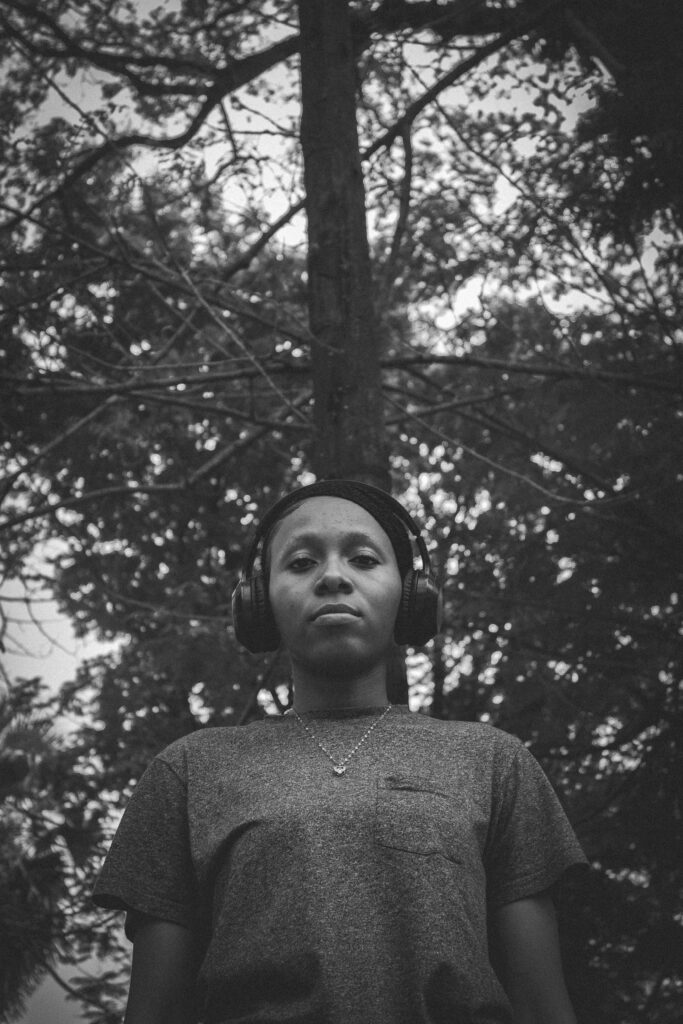 a woman wearing headphones standing in front of a tree